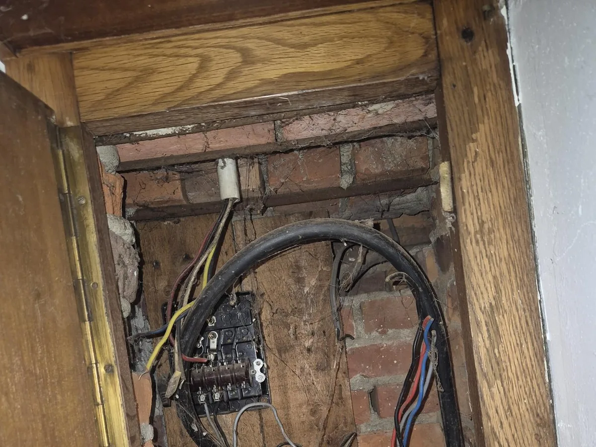 Geopende houten meterkast met zichtbare bedrading tijdens een elektriciteitskeuring